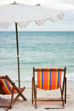 Two chairs and umbrella on the beach clipart