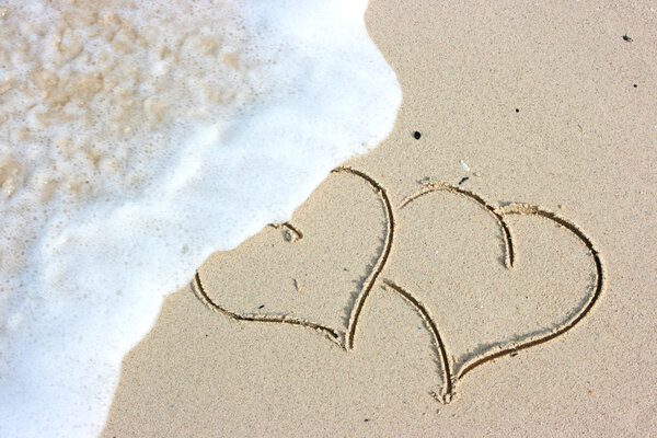 Two hearts drawing on the sandy beach