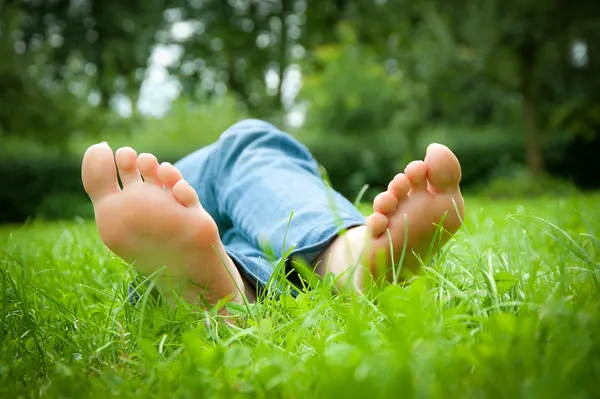 Nohy mladé ženy ležící v trávě — Stock fotografie
