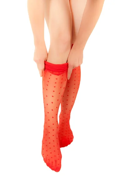 Женщина с тонкими ногами натягивает красные колготки — стоковое фото