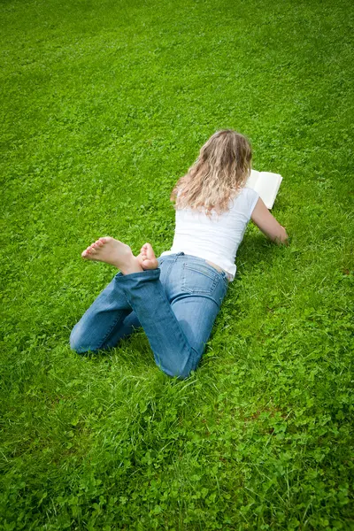 Joven rubia rizada leyendo un libro en un parque —  Fotos de Stock