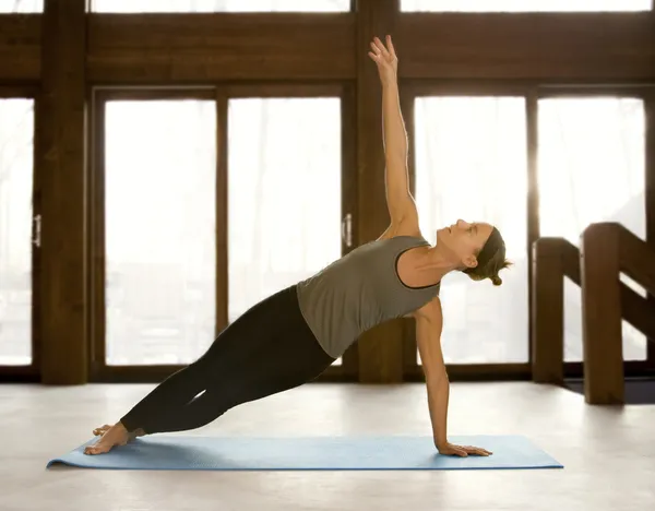 Passar kvinnan gör yoga positioner i en yoga-studio — Stockfoto