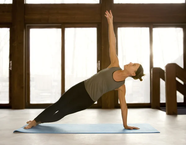 Passar kvinnan gör yoga positioner i en yoga-studio Stockbild