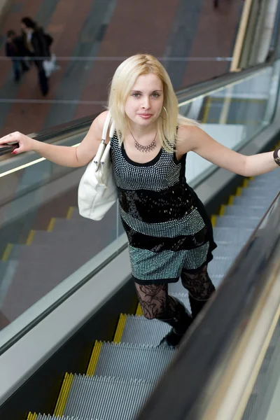 Schöne junge Frau geht auf Rolltreppe — Stockfoto