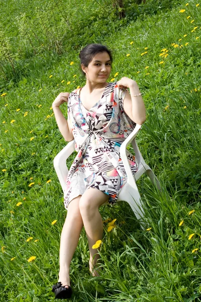 Dandelions arasında bir sandalyede oturan kız — Stok fotoğraf