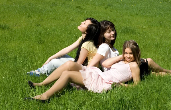 Drie meisjes zitten op gras — Stockfoto