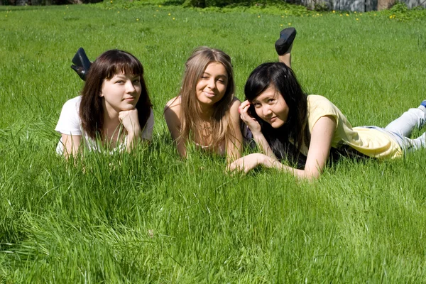 Drie meisjes liggen op gras — Stockfoto