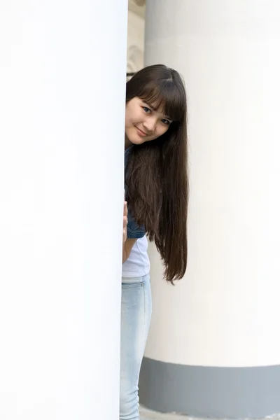 Flickan gömmer sig bakom kolumn — Stockfoto