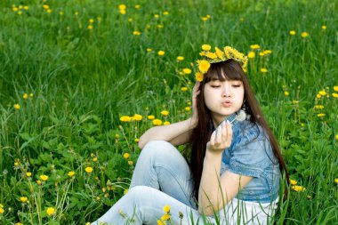 Dandelions arasında oturan kız