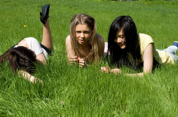 Tres chicas tumbadas en la hierba — Foto de Stock