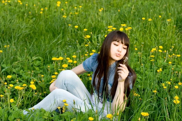 Dandelions arasında oturan kız — Stok fotoğraf