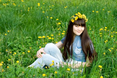 Dandelions arasında oturan kız