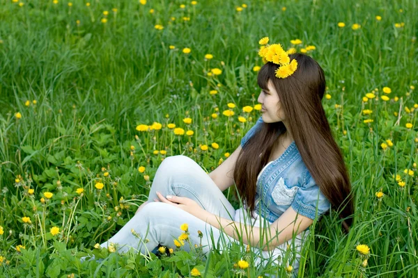 Girl sitting among dandelions — Stock Photo, Image