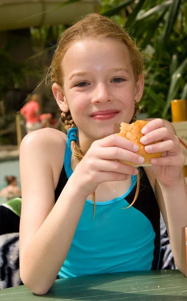 Dívka v bazénu plavat jíst chléb — Stock fotografie