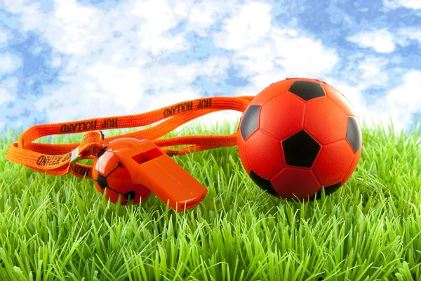 Bola de fútbol naranja y flauta sobre hierba —  Fotos de Stock