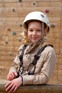 Young girl posing before climbing wall clipart