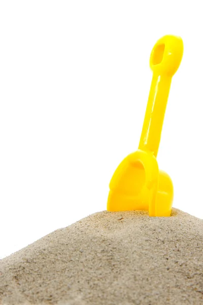Песчаная куча с желтой игрушечной лопатой — стоковое фото