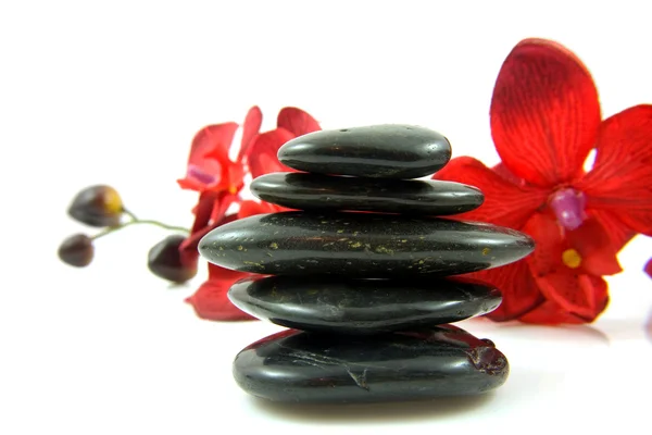 Gestapelde zwarte spa stenen met zijde orchid — Stockfoto