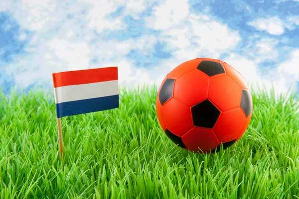 Bola laranja e bandeira holandesa no campo de futebol — Fotografia de Stock