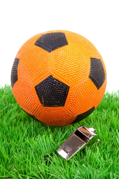 Bola de fútbol naranja y flauta sobre hierba — Foto de Stock