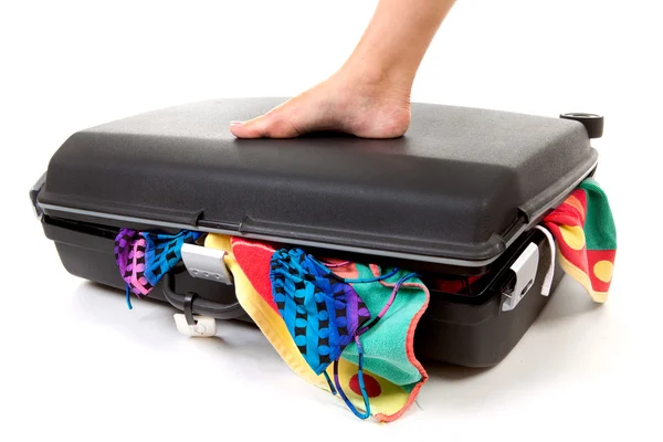 Foot on stuffed suitcase — Zdjęcie stockowe
