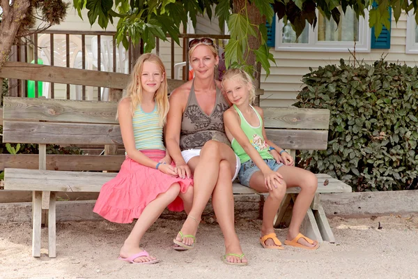 Mother and daughters sitting on a wooden bench — Stock Photo, Image