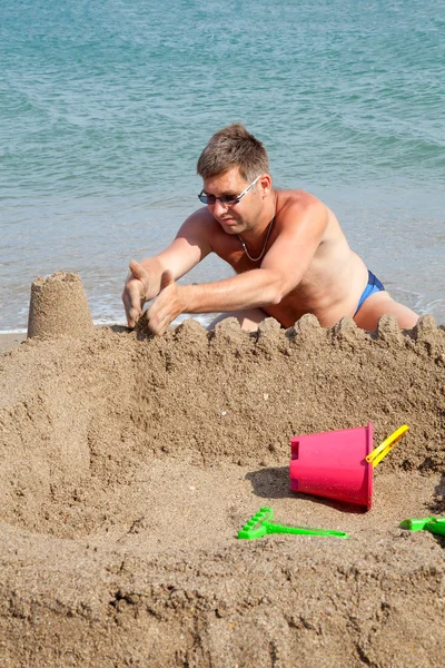 Stock image Man is making sandcastle on the beach