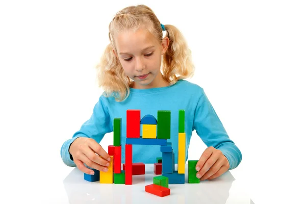 Menina está brincando com blocos de madeira coloridos — Fotografia de Stock