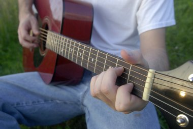 Adam akustik gitar çalıyor.