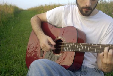 Adam akustik gitar çalıyor.