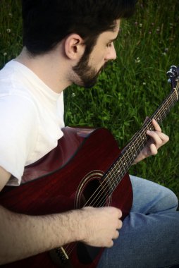 Adam akustik gitar çalıyor.