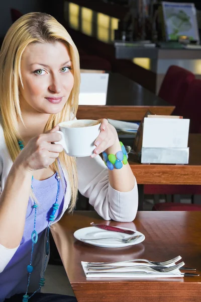 Νεαρή γυναίκα πίνει καφέ στο καφέ — Φωτογραφία Αρχείου