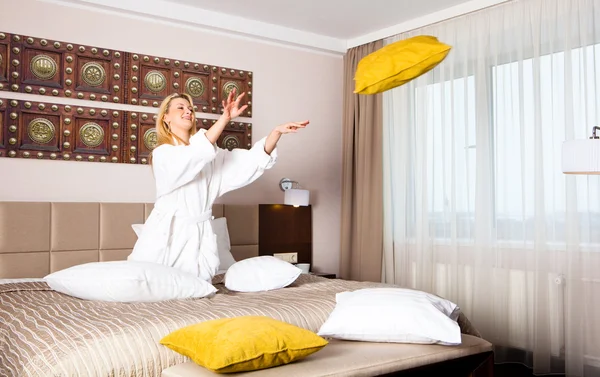 Mujer joven jugando con almohadas en la cama — Foto de Stock