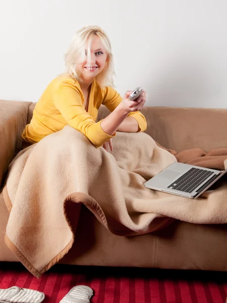 Mujer joven con ordenador y TV a distancia — Foto de Stock