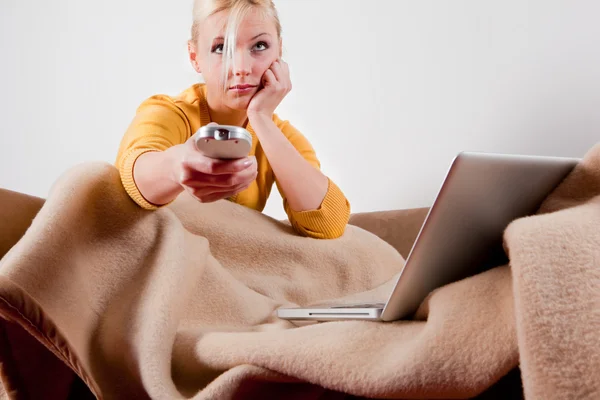 Young woman with computer and TV remote — Stock Photo, Image