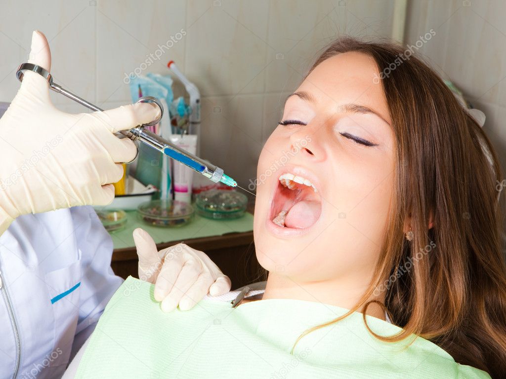 Dentist making shot for woman patient