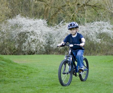 A young six year old boy riding his bke clipart