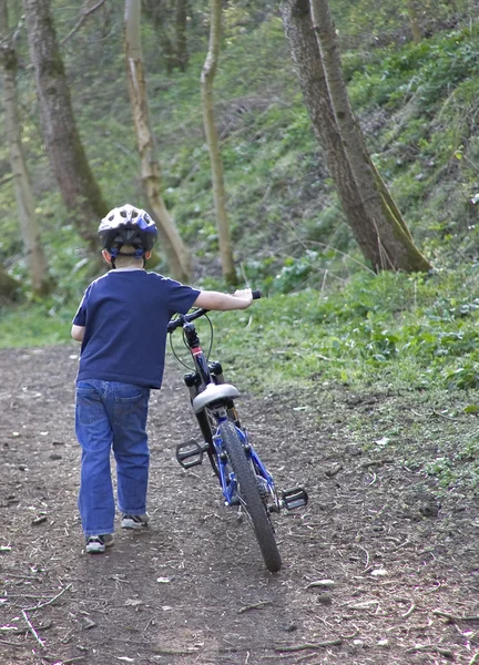 Молодой шестилетний мальчик толкает свой велосипед — стоковое фото