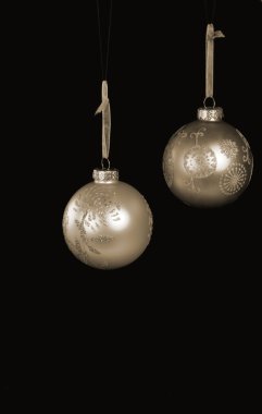 Two golden christmas baubles against a black background clipart