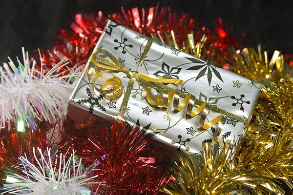 Ein verpacktes Weihnachtsgeschenk umgeben von Lametta — Stockfoto