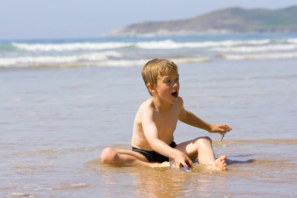 Молодий хлопчик грає на краю океану — стокове фото