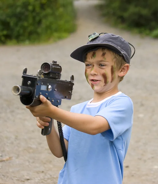 En ung pojke med kamouflage färg på hans ansikte som förbereder sig för att spela — Stockfoto