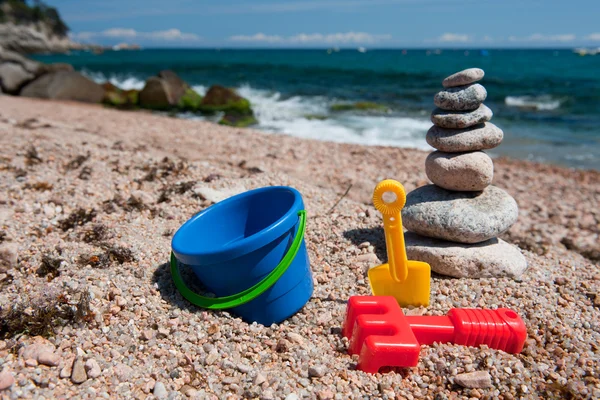 Stranden med staplade stenar och leksaker — Stockfoto