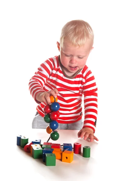 Baby boy is playing with wooden beads — Stock Photo, Image