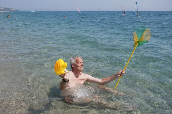 Elderly man is playing in the sea — Stock Photo, Image