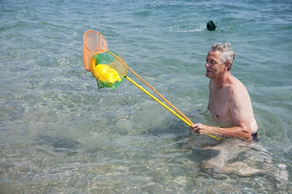Elderly man is playing in the sea — Stock Photo, Image