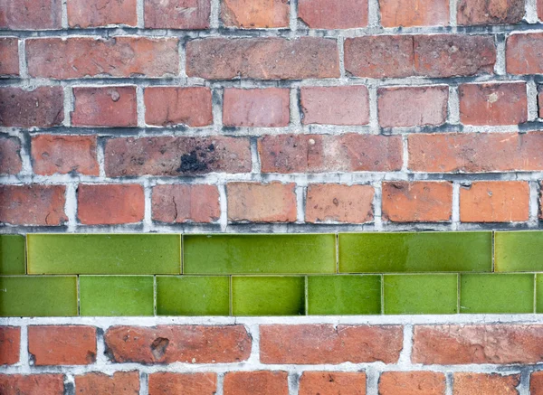 Vieux mur de briques rouges avec rangée de carreaux d'émail vert — Photo