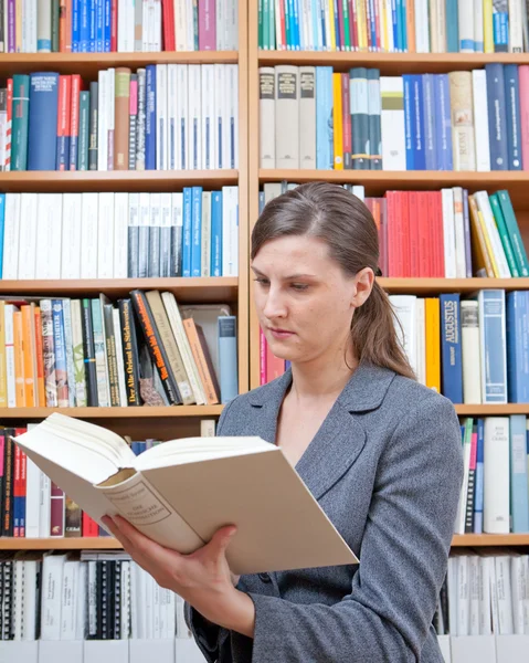 stock image Young woman reading a book in the library