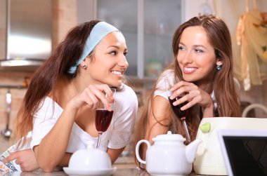 Happy women with wine in kitchen clipart