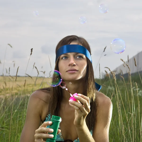 Promyšlené žena fouká mýdlové bubliny — Stock fotografie